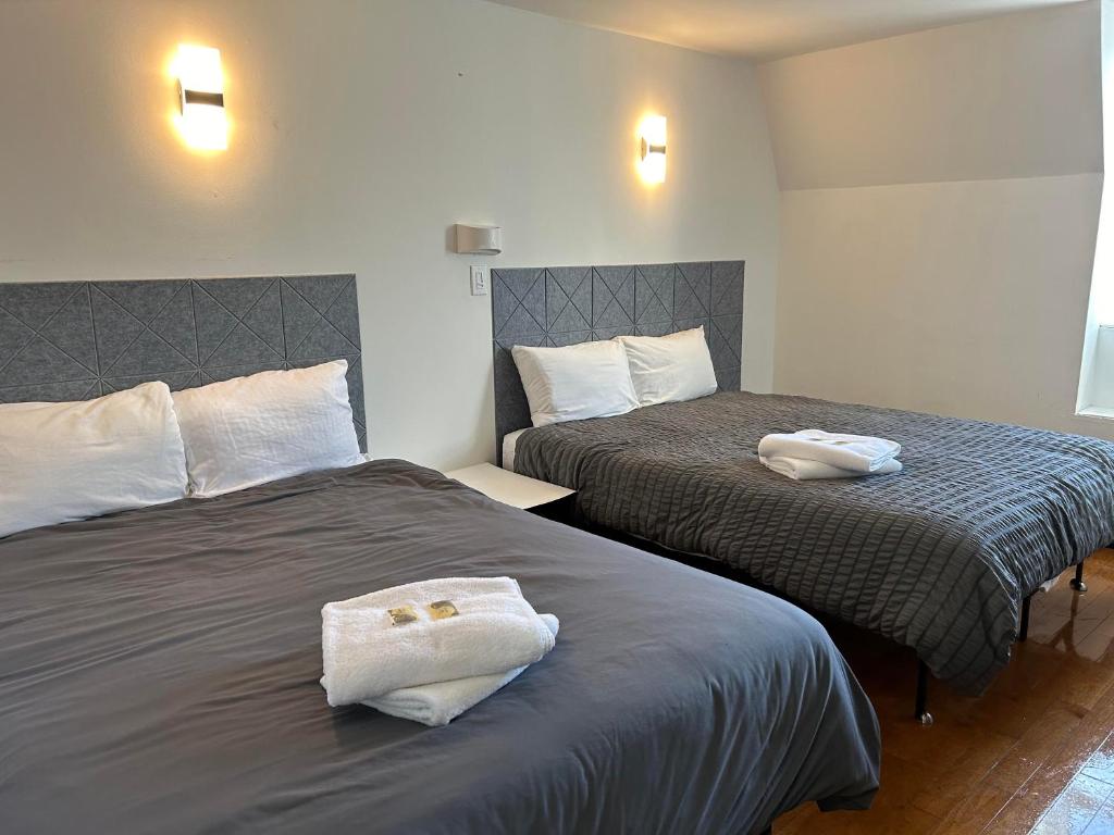 2 Betten in einem Hotelzimmer mit Handtüchern darauf in der Unterkunft APD HOTEL in Montreal