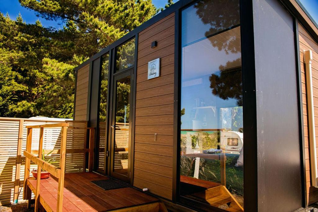 a tiny house with large windows on a deck at Pacific View in Leithfield
