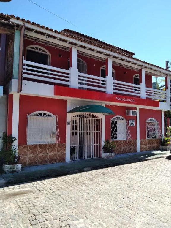 czerwony budynek z bramą przed nim w obiekcie Pousada Ray Sol - Centro Arraial d Ajuda w mieście Porto Seguro