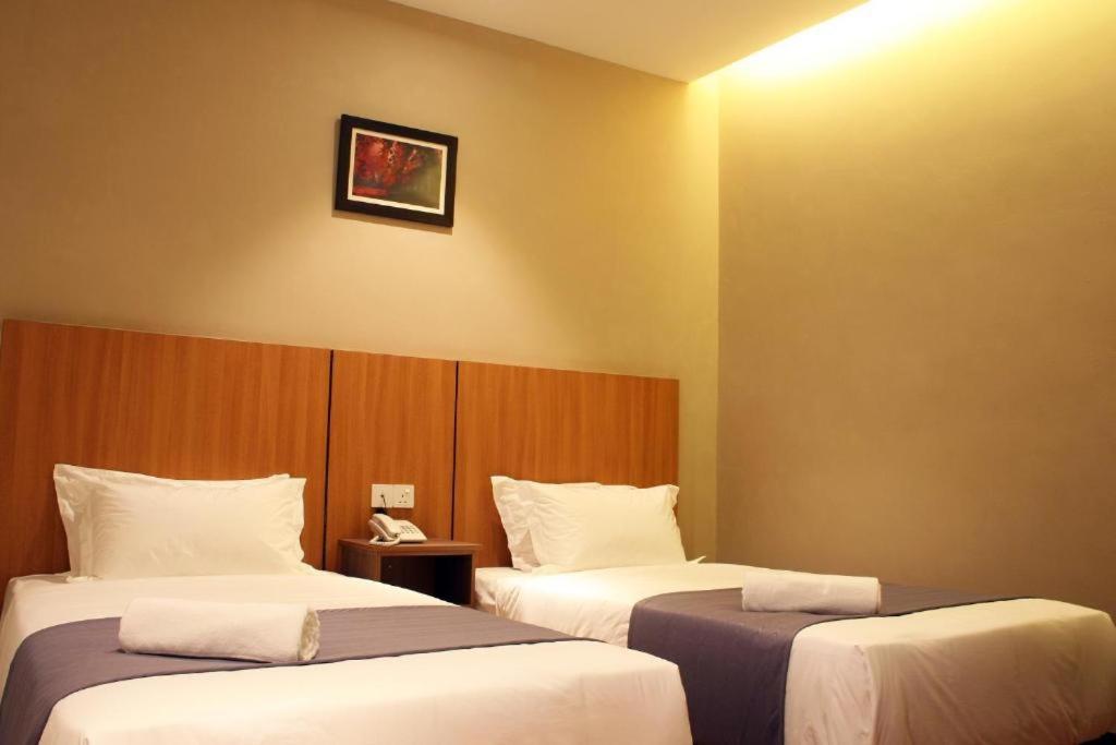 a hotel room with two beds and a clock on the wall at MELUR HOTEL BANGI GATEWAY in Bandar Baru Bangi