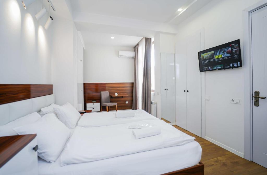 ein weißes Schlafzimmer mit einem weißen Bett und einem Schreibtisch in der Unterkunft Studio with balcony on Melikishvili, city center in Tbilisi City