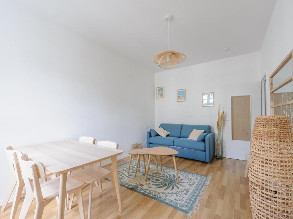 un salon avec une table et un canapé bleu dans l'établissement Studio Rénové à Deux Pas du Vieux Port avec Ascenseur - Idéal Pour 2! - FR-1-535-53, à La Rochelle