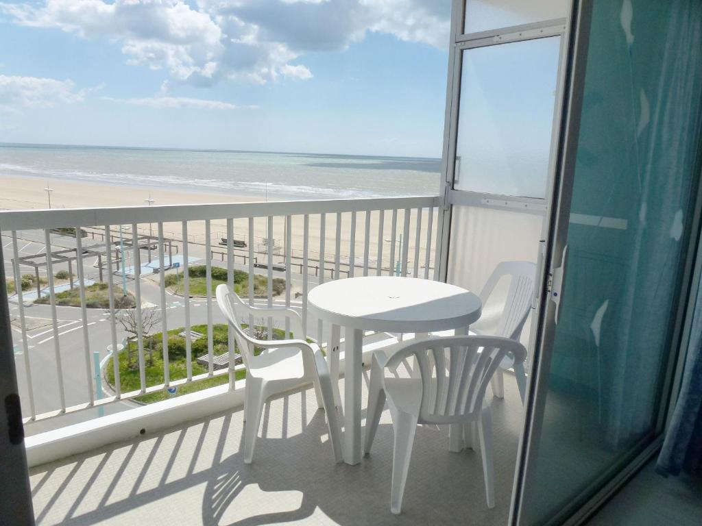 - un balcon avec une table et des chaises et la plage dans l'établissement Location Studio Spacieux - Proche Plage et Commerces - Animaux Admis - FR-1-323-416, à Saint-Jean-de-Monts