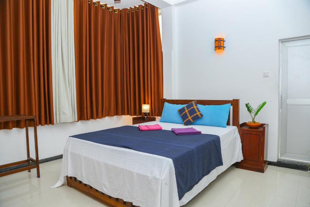 The Heavens Ocean Villa Talpe في تالبي: غرفة نوم مع سرير ووسائد زرقاء وردية