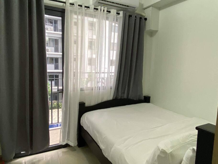 a bedroom with a bed and a large window at Shore Residence D22 shortwalk MOA Balconypoolview in Manila