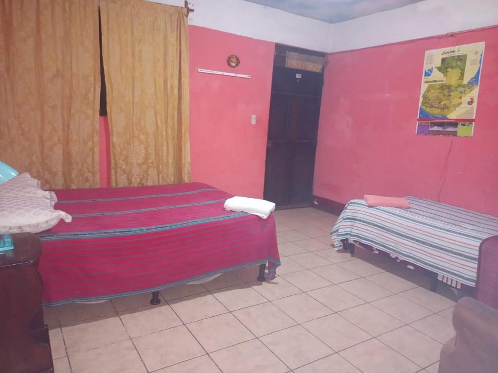 a room with two beds and a red wall at Casa Zope in Panajachel