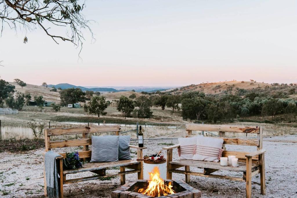 two benches sitting next to a fire pit at Canguri Boutique - A Memorable Farmstay near Mudgee in Mudgee
