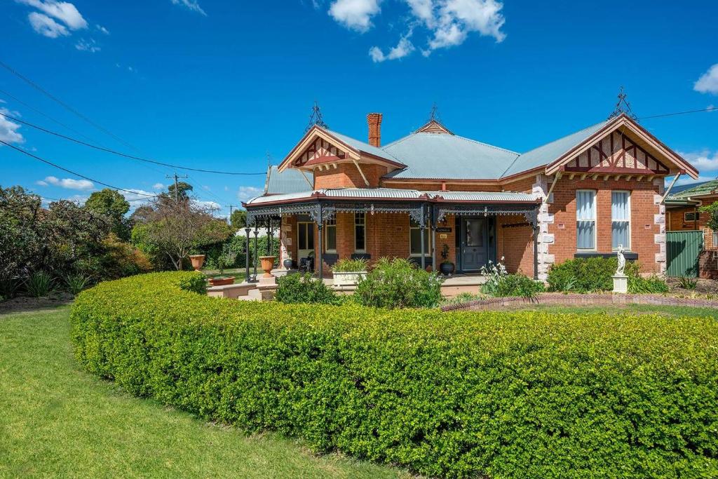 a large brick house with a green hedge at Luxury at Lauralla - An Elegant Victorian Escape in Mudgee