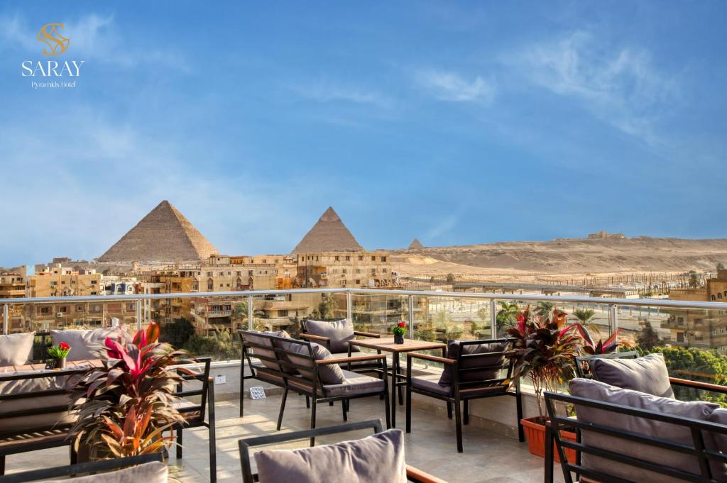 um pátio com mesas e cadeiras com vista para as pirâmides em Saray Pyramids & Museum View Hotel em Cairo
