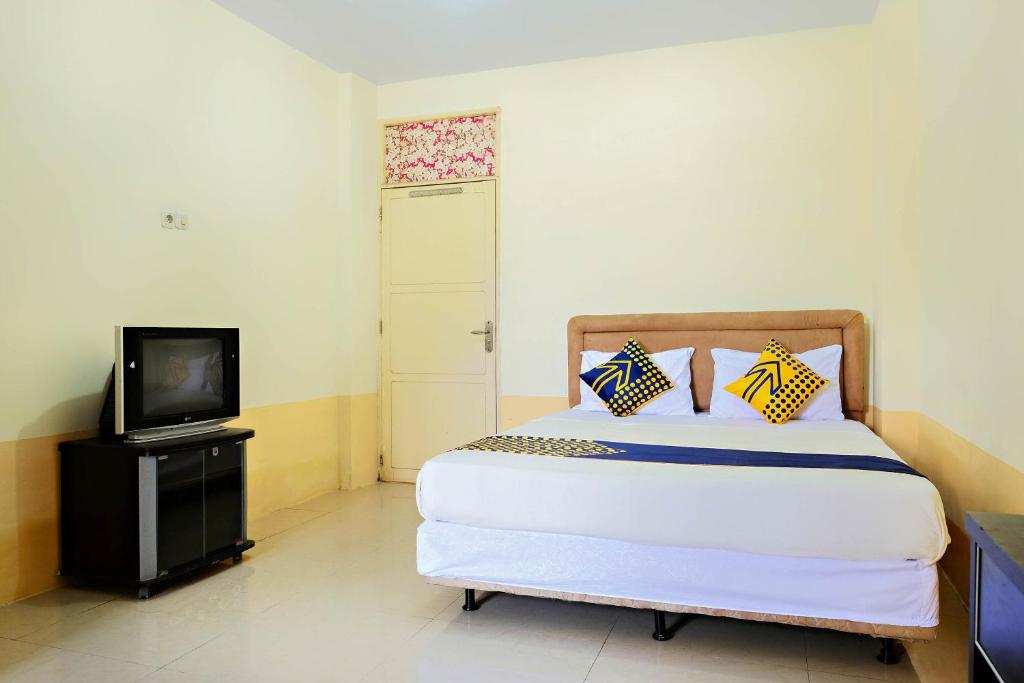 Schlafzimmer mit einem Bett, einem TV und einer Tür in der Unterkunft SPOT ON 2610 Zn Guest House in Makassar
