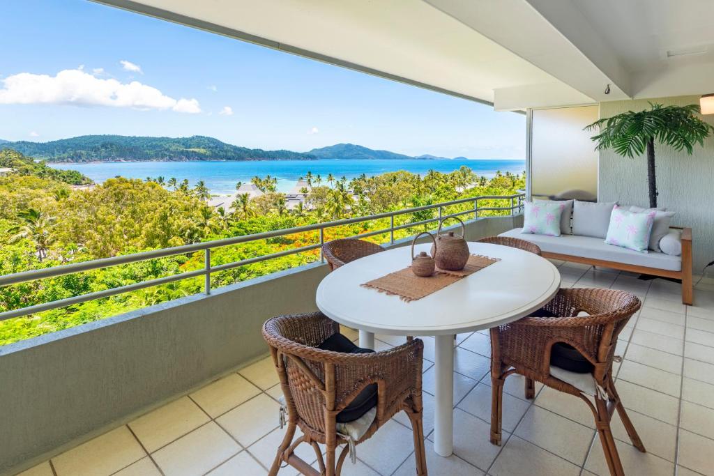 a balcony with a table and chairs and a view of the ocean at Poinciana Lodge - 2 bedroom - on Hamilton Island by HIHA in Hamilton Island