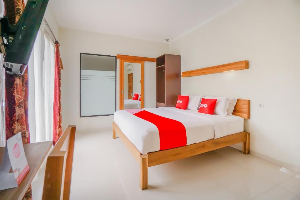 a bedroom with a bed with red pillows at OYO 90319 Angler Guest House Malang in Malang
