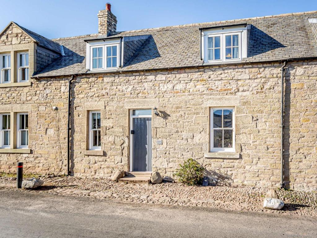 特維德上游的貝里克的住宿－2 bed in Berwick Upon Tweed 81273，街上有一扇蓝色门的石头房子