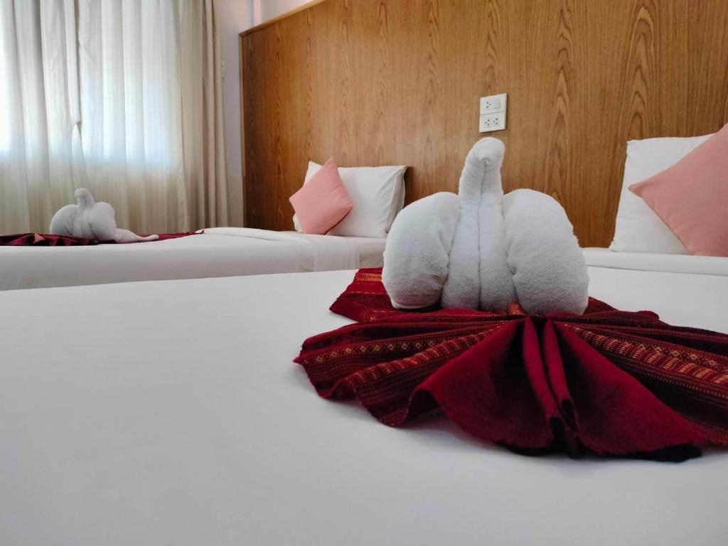 dos animales de peluche sentados en una cama en una habitación de hotel en S2S Queen Trang Hotel, en Trang