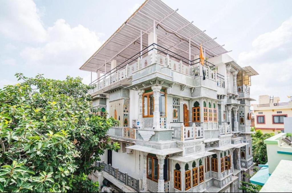 a white house with a balcony and trees at Lassi Guest House in Udaipur