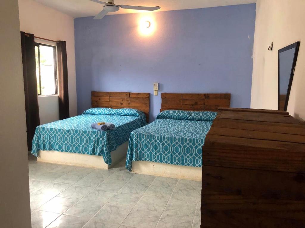 two beds in a bedroom with blue walls at El bungaló in Tecolutla