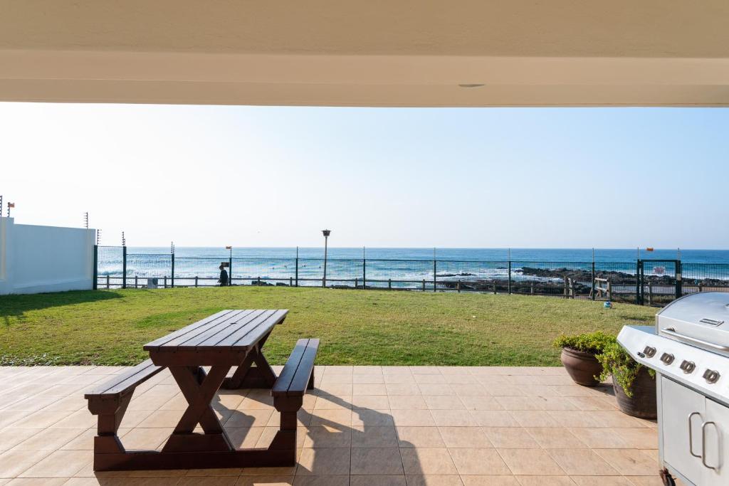 a picnic table on a patio with a view of the beach at La Mustique 4 in Ballito