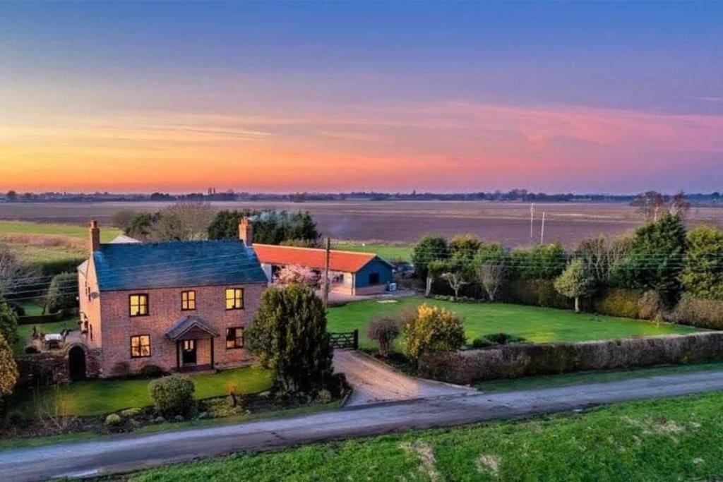 an aerial view of a farm house with a sunset in the background at Private garden annexe with kitchenette in Gedney