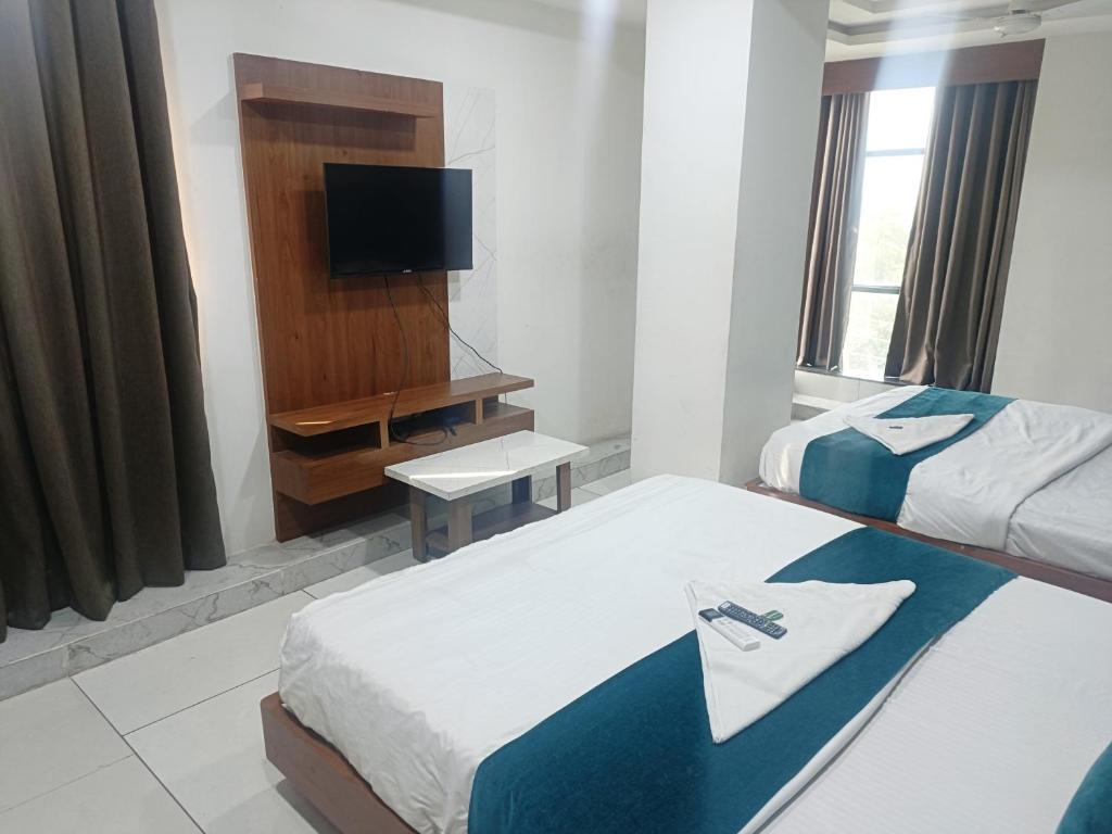 a hotel room with two beds and a television at ROYAL PRIME HOTEL in Vadodara