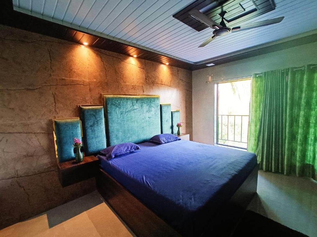 a bedroom with a blue bed with a window at The Grand Inn in Nirmal