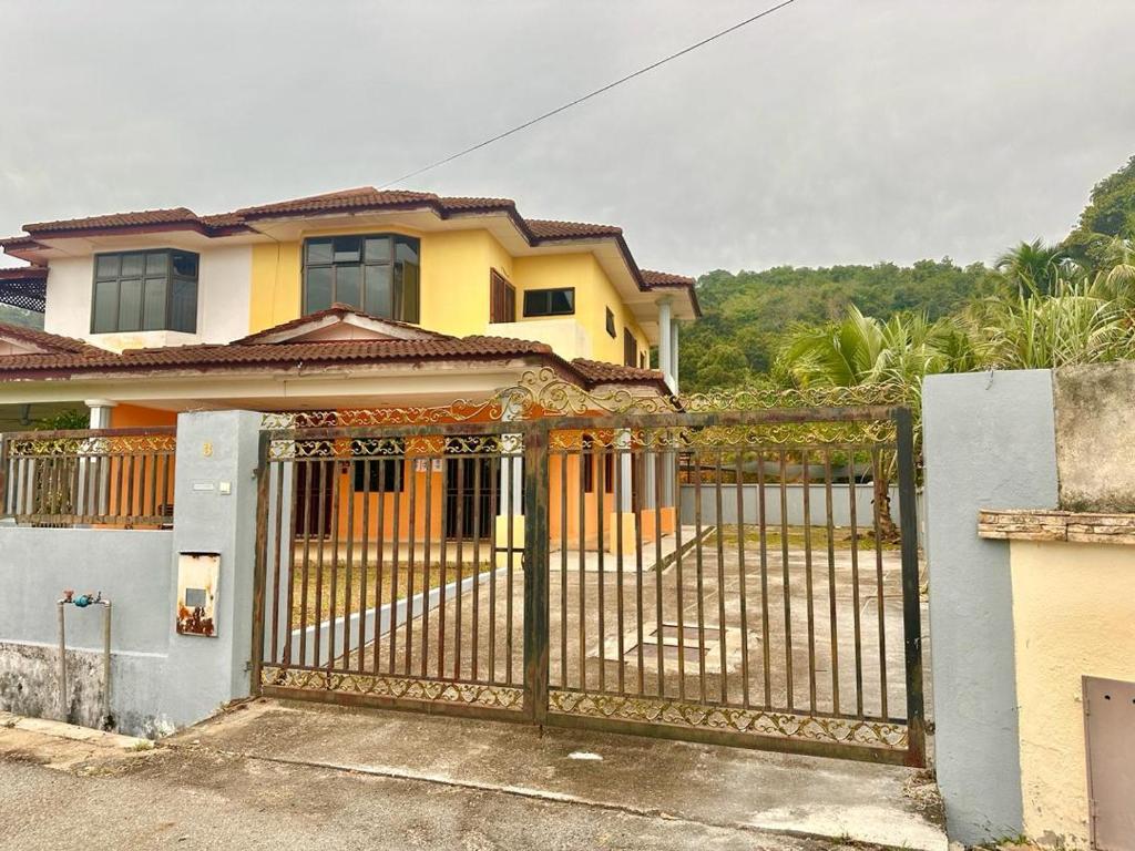 ein gelbes Haus mit einem Tor davor in der Unterkunft Meranti Homestay in Bentong