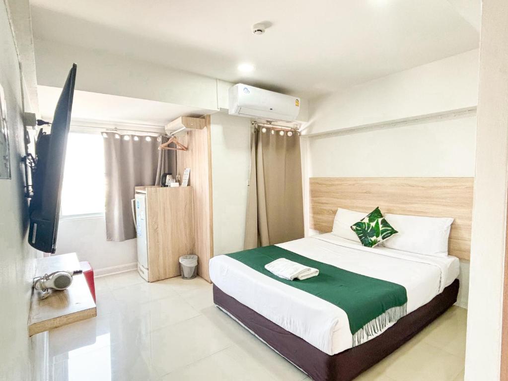 Compact guest room with a double bed, wall-mounted TV and curtained window.