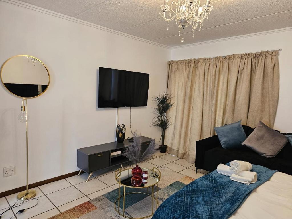 a living room with a couch and a flat screen tv at Premium Apartment In Fourways in Sandton