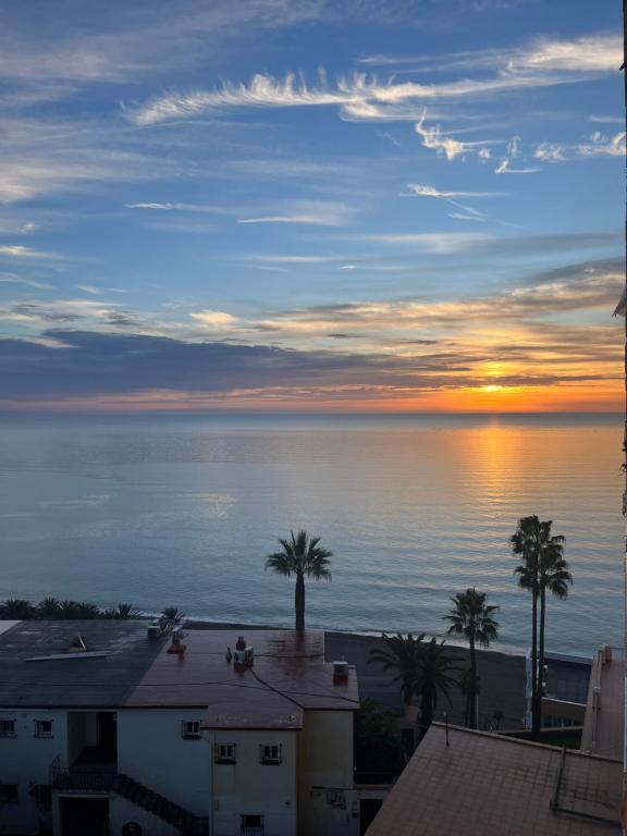 - une vue sur l'océan au coucher du soleil avec des palmiers dans l'établissement Apartamento Torre de la Roca Torremolinos, à Torremolinos