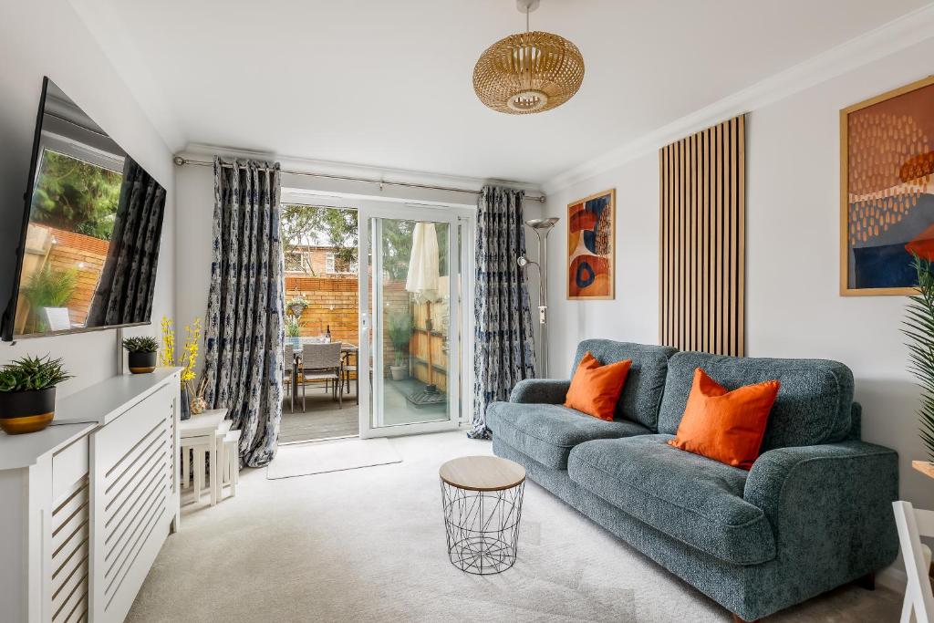 uma sala de estar com um sofá azul e almofadas laranja em Modern, comfy Town centre gem, near beach, parking em Bournemouth