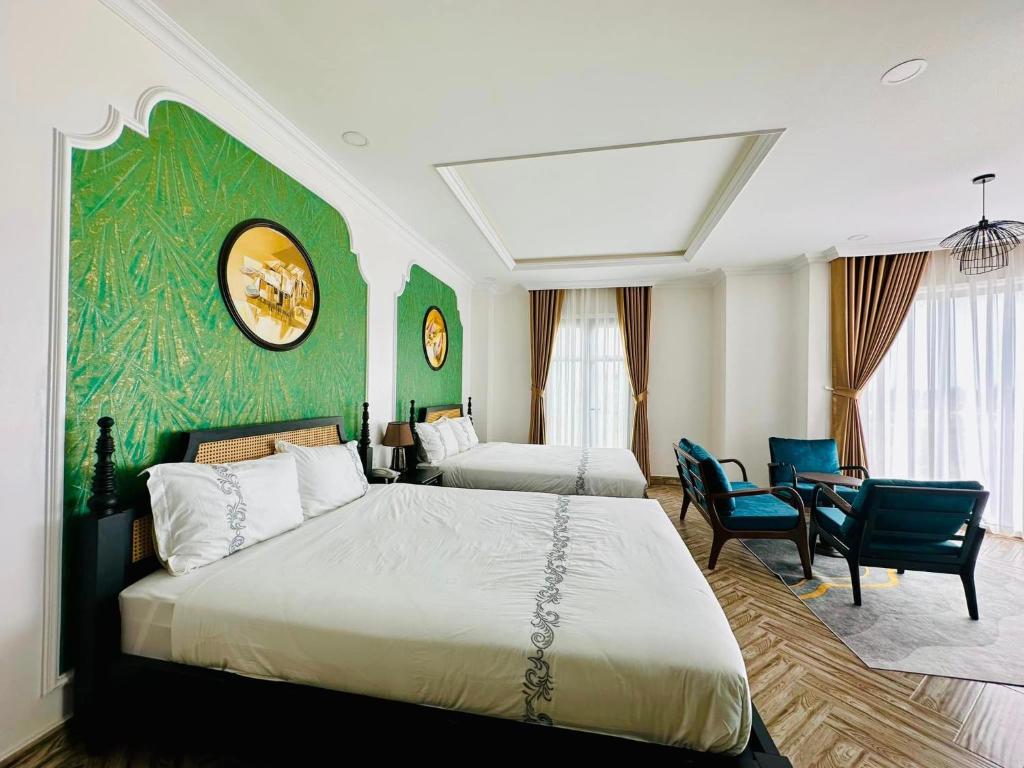 um quarto com 2 camas e uma parede verde em Khách Sạn The One Hotel 2 em Cà Mau