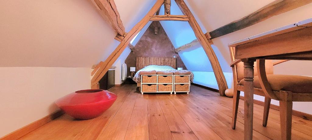 Pokój na poddaszu z łóżkiem i drewnianą podłogą w obiekcie Chambre nature w mieście Thibivillers