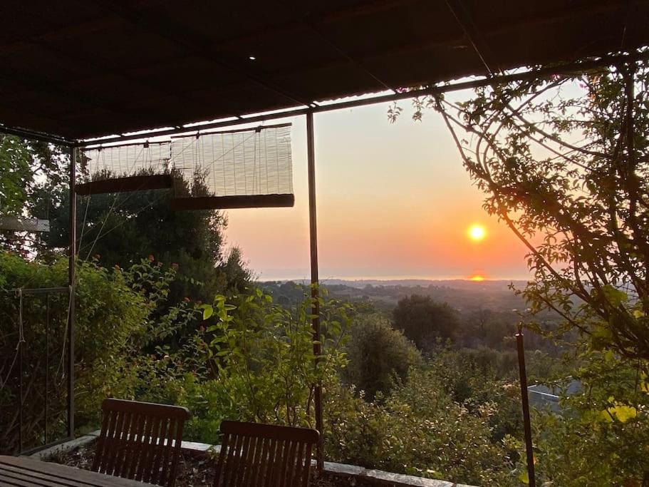 einen Blick auf den Sonnenuntergang von einer Veranda mit 2 Bänken in der Unterkunft Tranquillité ,vue mer in Chiatra
