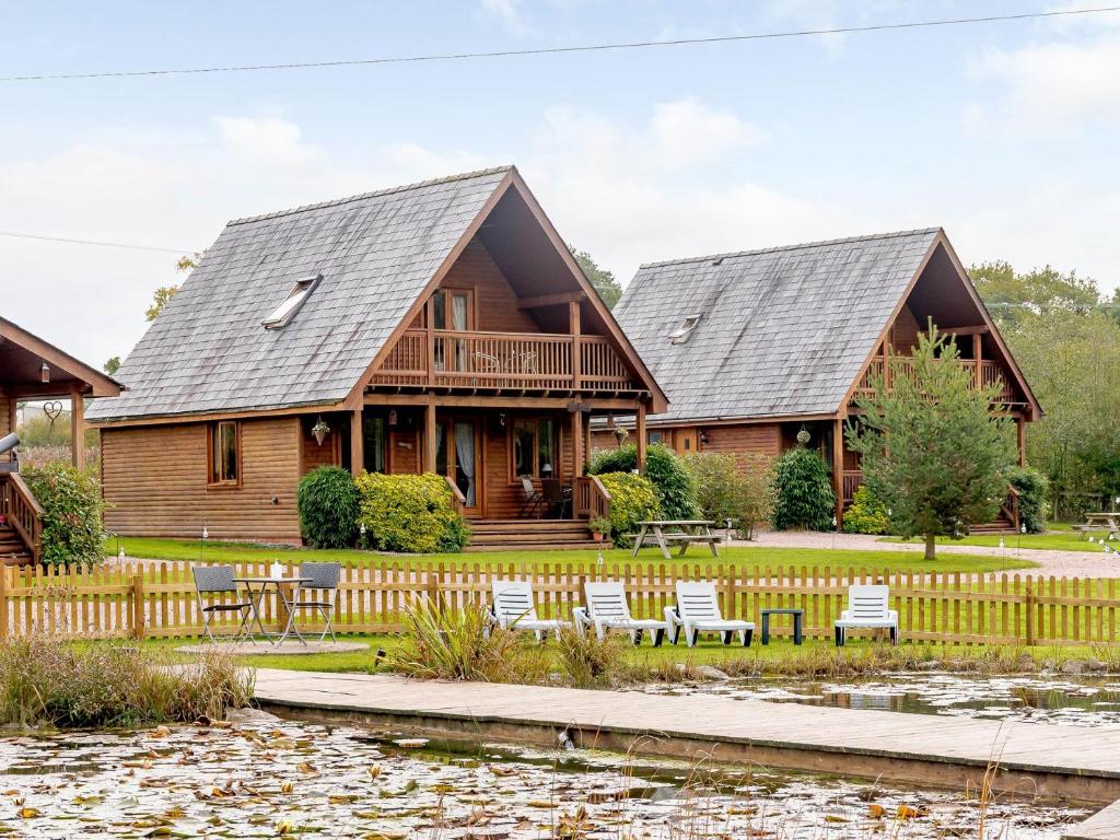 two log homes with a deck and a pond at 3 Bed in Ledbury 77378 