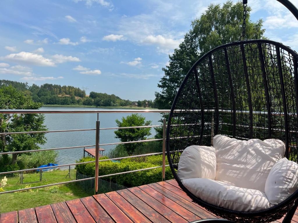 a swing on a deck with a view of a lake at Wakacyjny Hartowiec 2 in Grodziczno