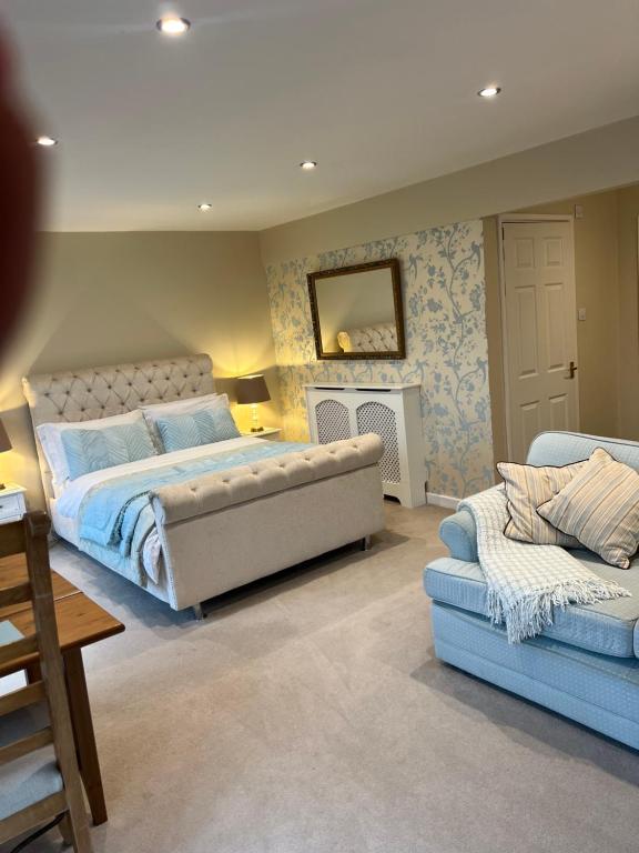 a bedroom with a bed and a couch and a fireplace at Highcroft House in Corsham