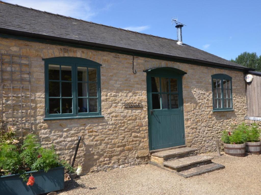 a brick building with a green door and windows at 1 Bed in Bourton-on-the-Water 44960 in Withington
