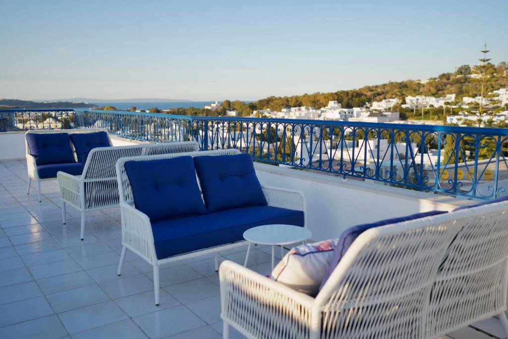 Misk Villa - Boutique Hotel & Spa في سيدي بو سعيد: صف من الكراسي والطاولات على الشرفة