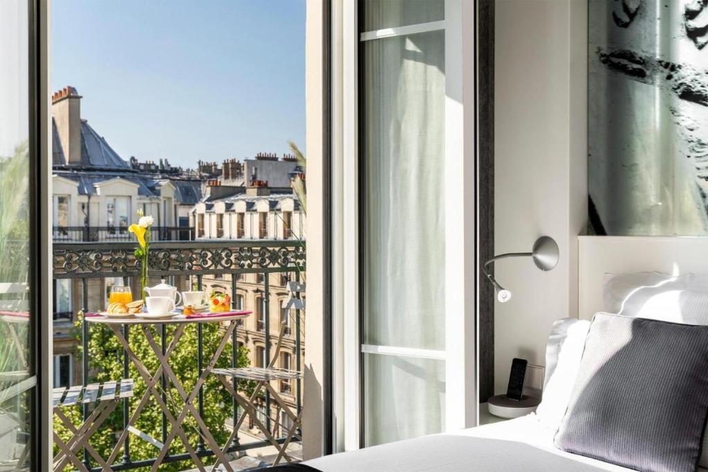 Zimmer mit einem Bett und einem Balkon mit einem Tisch in der Unterkunft Chambre avec terrasse à Montmartre Sacré Coeur in Paris