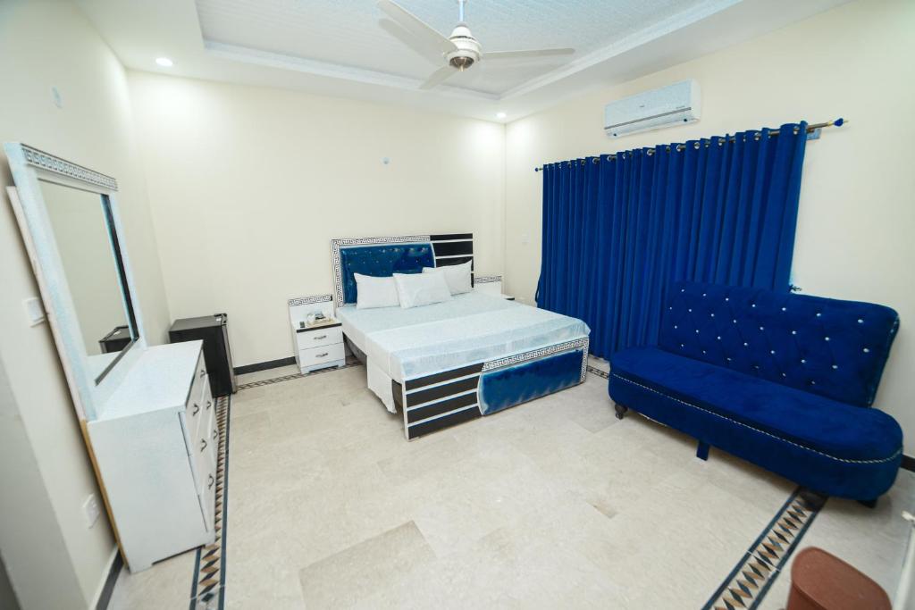 um quarto com uma cama e uma cadeira azul em Royal Blue Inn House em Islamabad