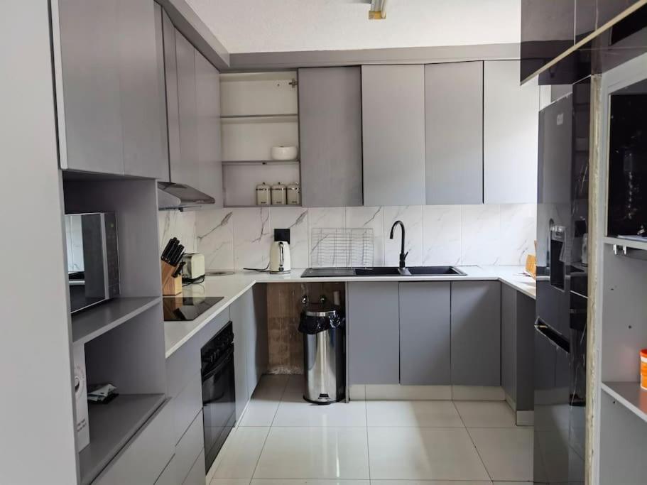 una cocina con armarios blancos y un cubo de basura en Beautiful apartment behind Illanga Mall en Mataffin