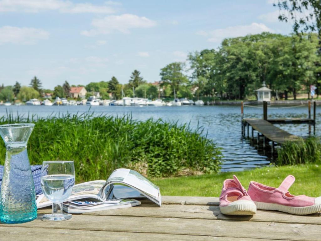 una mesa con libros y zapatos y un vaso de agua en Klein Seeland, en Schwielowsee