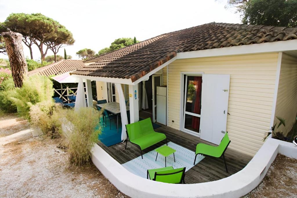 una casa con terraza y sillas verdes en GASMIM29 - Golfe de St-Tropez, chalet climatisé dans domaine arboré, en Gassin