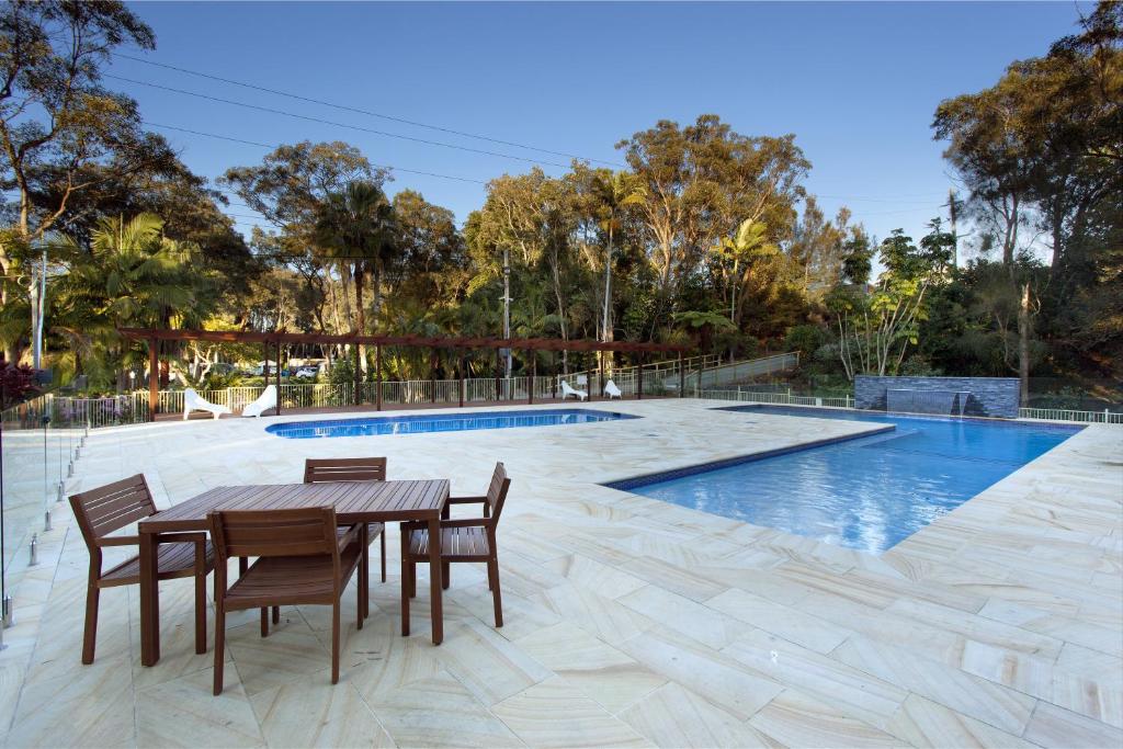 a patio with a table and chairs next to a pool at Sapphire Beach Holiday Park in Coffs Harbour
