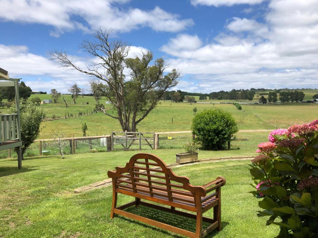 a wooden bench sitting in the grass in a field at Toscana on Greenhills in Sutton Forest