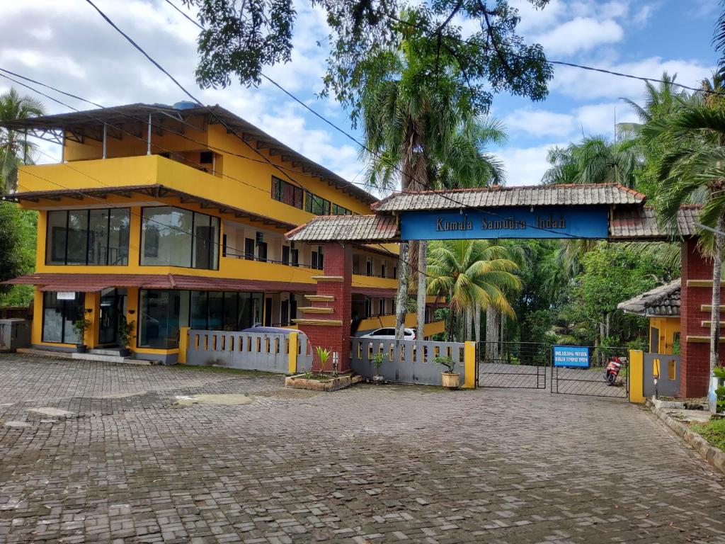 un edificio amarillo y rojo con una puerta delante en Hotel kumala samudra, en Tjikakaka
