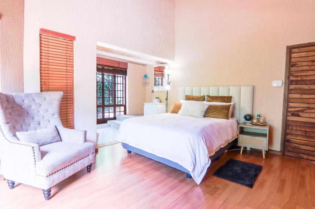 ein Schlafzimmer mit einem Bett und einem Stuhl in der Unterkunft Airbnb at Bailyes in Pretoria