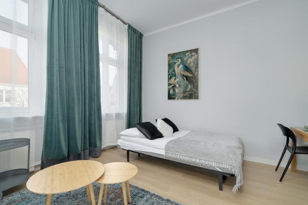 een slaapkamer met een bed met groene gordijnen en een tafel bij Stylish Grey Apartments with a City View in Poznań by Renters in Poznań