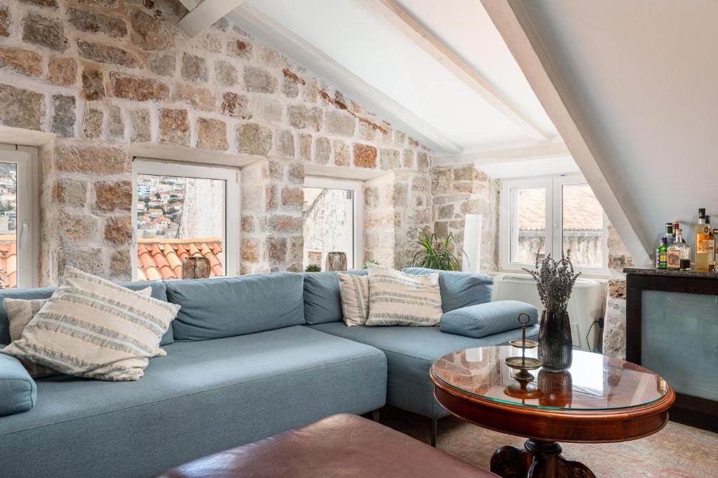 uma sala de estar com um sofá azul e uma parede de pedra em Villa Mirabilis, stunning superior villa, Dubrovnik Old Town em Dubrovnik