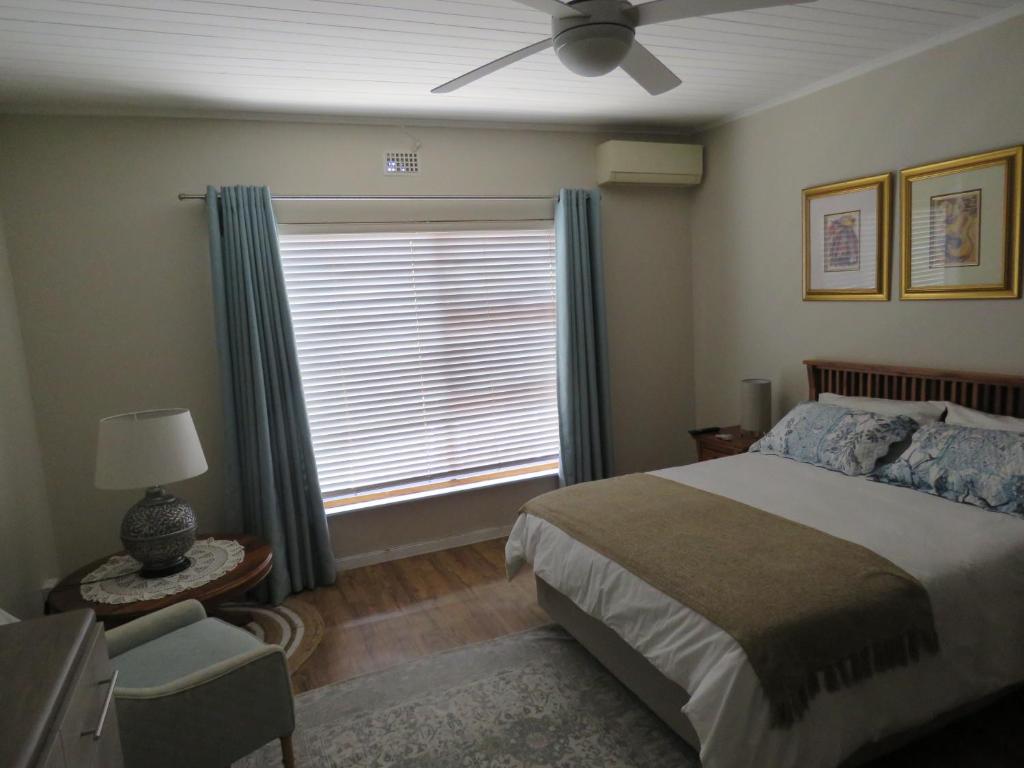 Avo Tree Guesthouse في بارل: غرفة نوم مع سرير ونافذة مع مروحة سقف