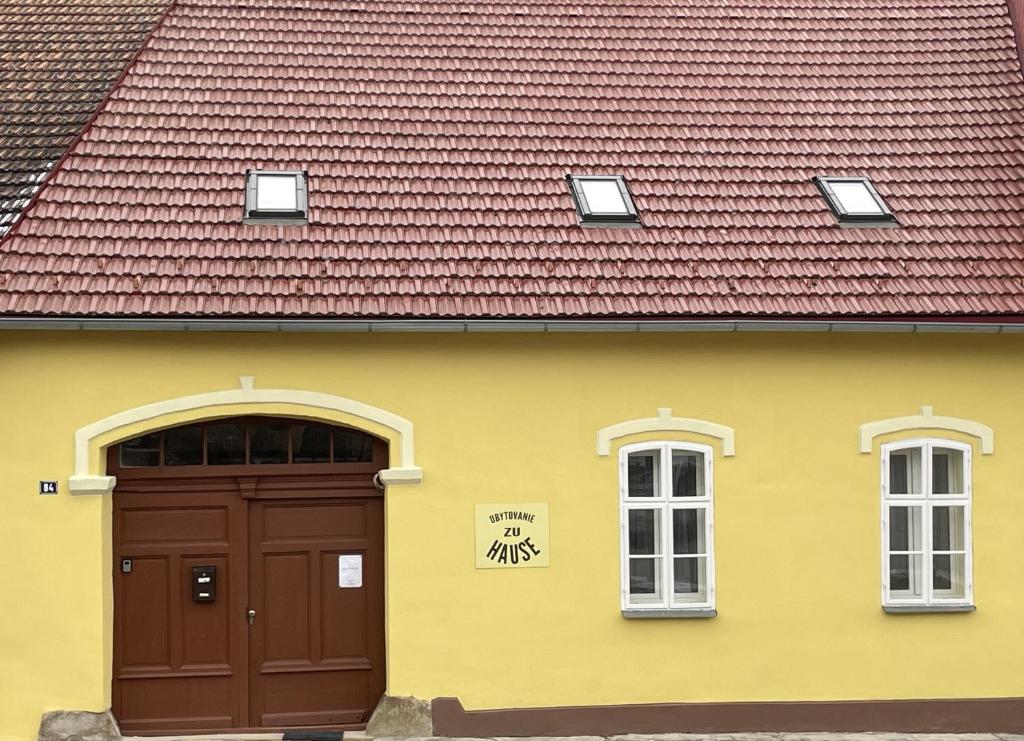a yellow building with a brown door and a red roof at Zu Hause in Vrbov